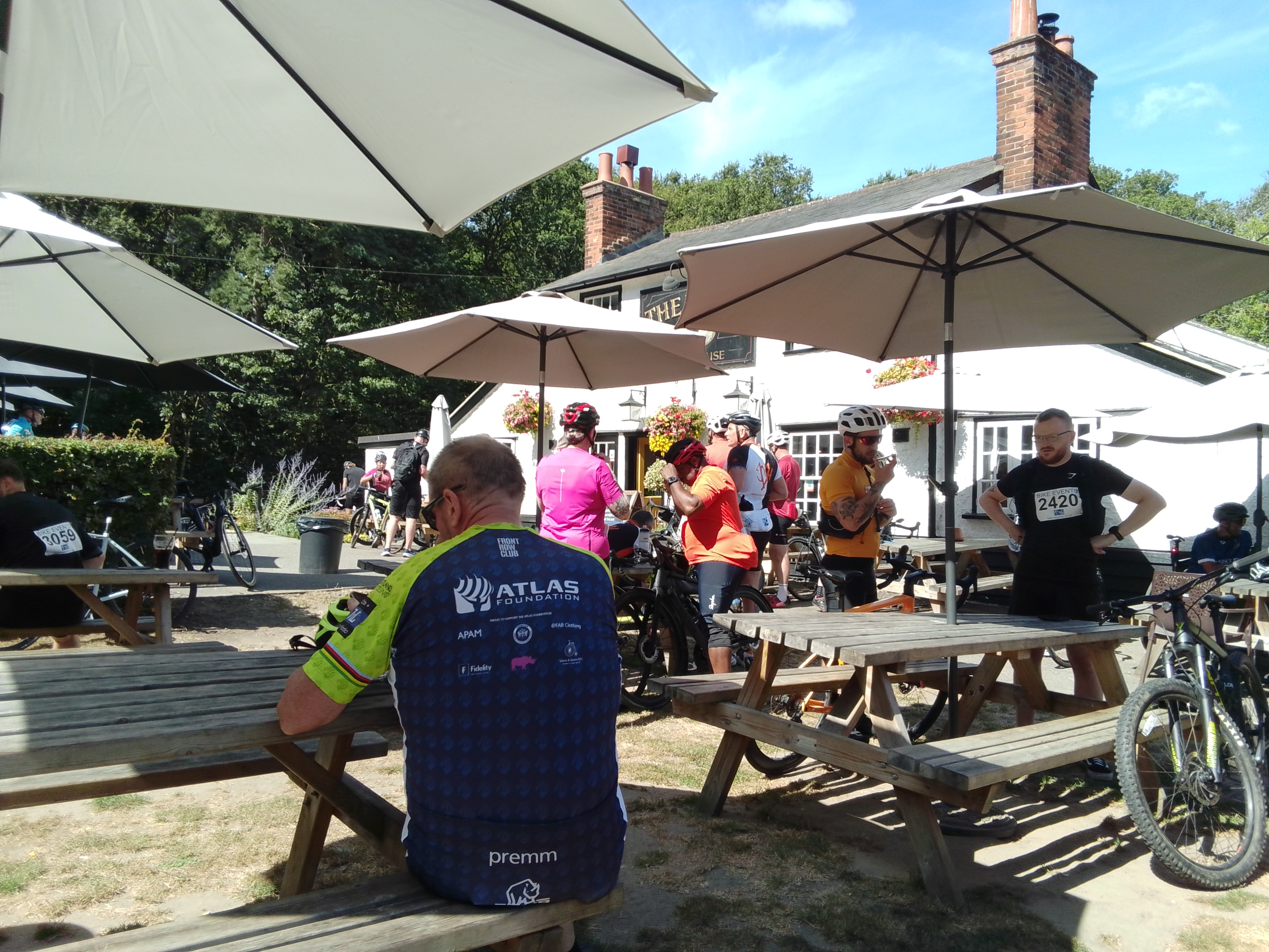 Cyclists resting under pub umbrellas